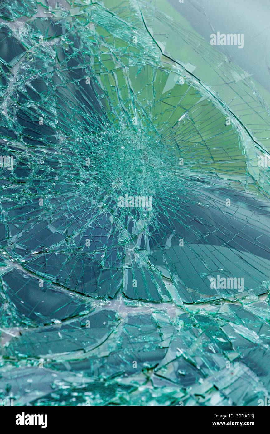 Gros plan du verre de sécurité vert brisé avec des fissures complexes. Motif de verre trempé brisé montrant des lignes de fracture radiales. Banque D'Images