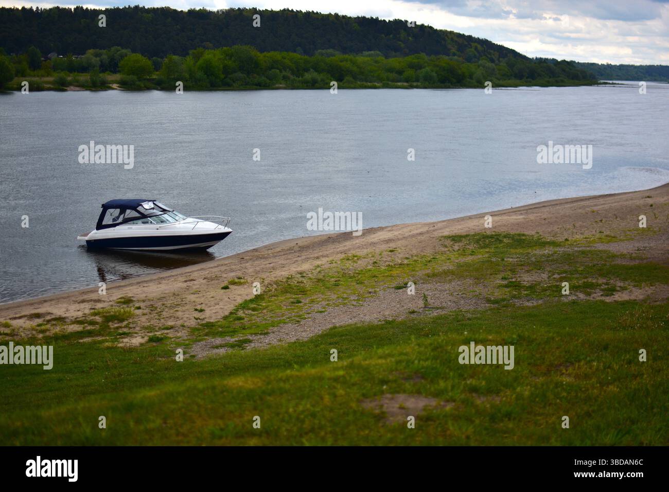 Un petit yacht à moteur amarré sur la rive de la rivière. Bateau à moteur ancré au bord de la rivière. Banque D'Images