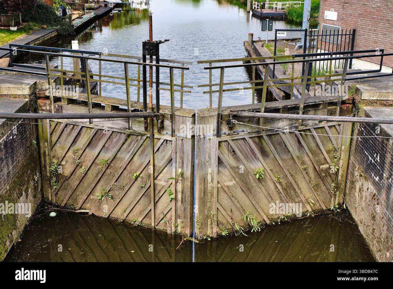 25 avril 2022 - Strijensas-pays-Bas : double écluse en bois actionnée manuellement partiellement envahie par des plantes aquatiques, toujours en condition fonctionnelle Banque D'Images
