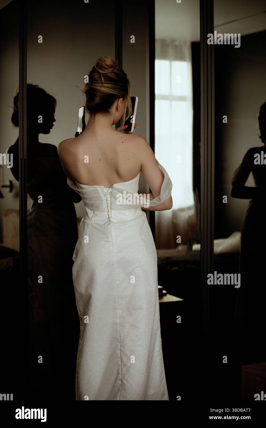 La mariée se regarde dans le miroir et prend une photo d'elle-même au téléphone Banque D'Images
