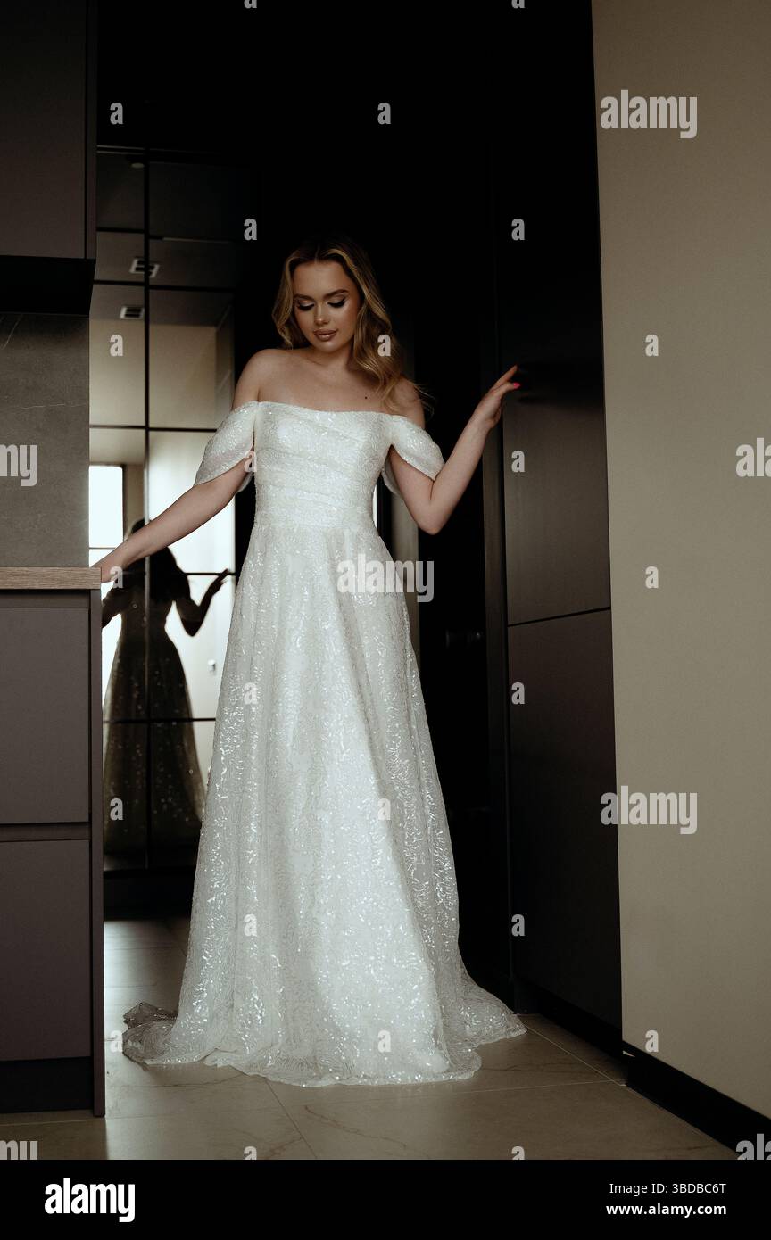 Robe de mariée élégante présentée dans un intérieur minimaliste avec modèle en pose chic Banque D'Images