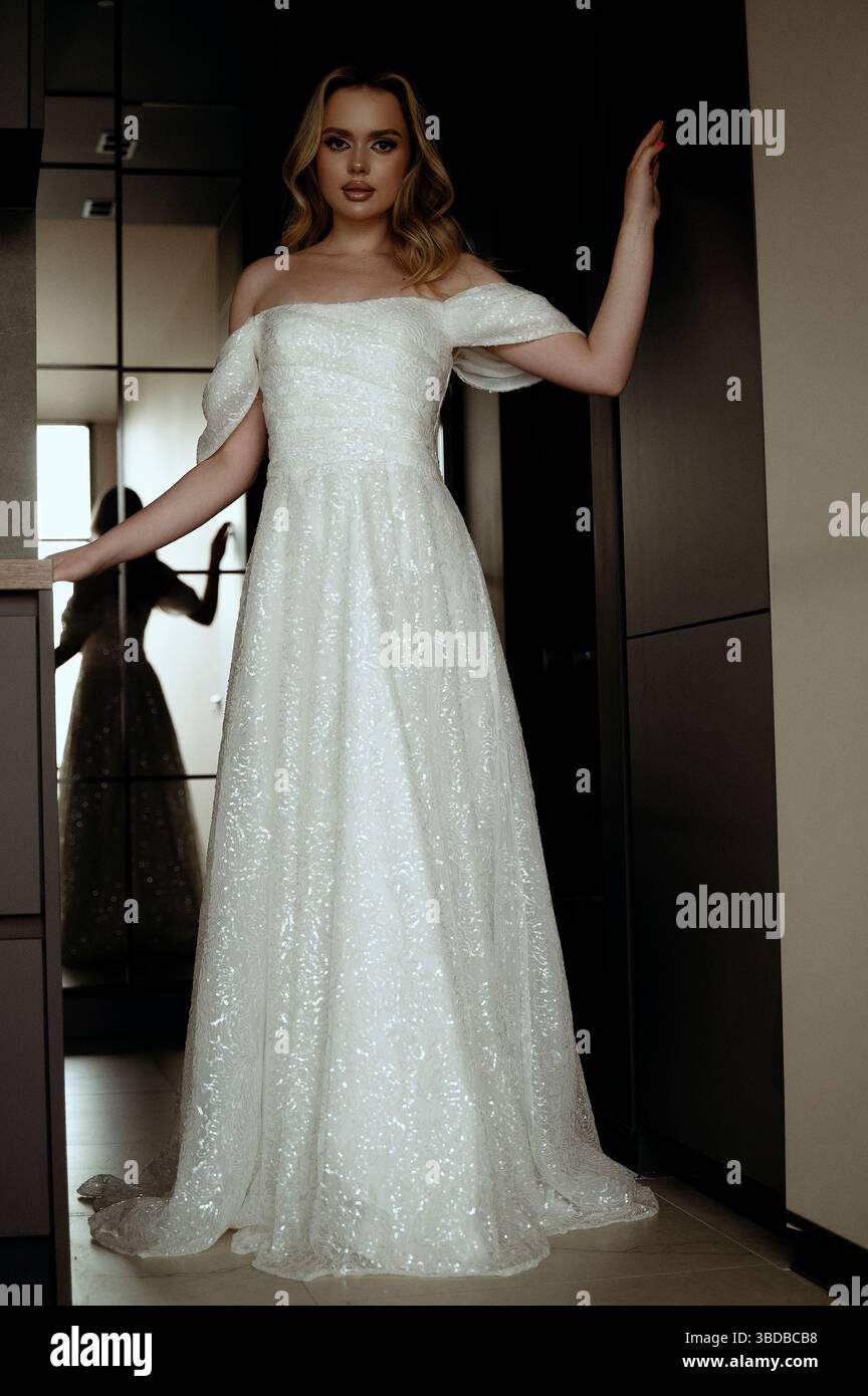Robe de mariée élégante présentée dans un intérieur minimaliste avec un modèle dans une pose chic Banque D'Images