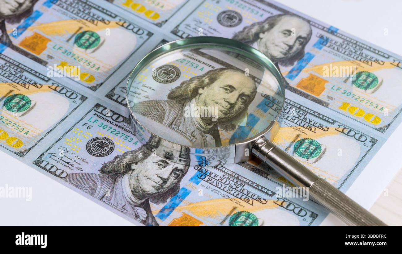La loupe met en évidence les détails du billet de cent dollars américains mettant en vedette Benjamin Franklin crée une ambiance d'investigation analytique. Banque D'Images