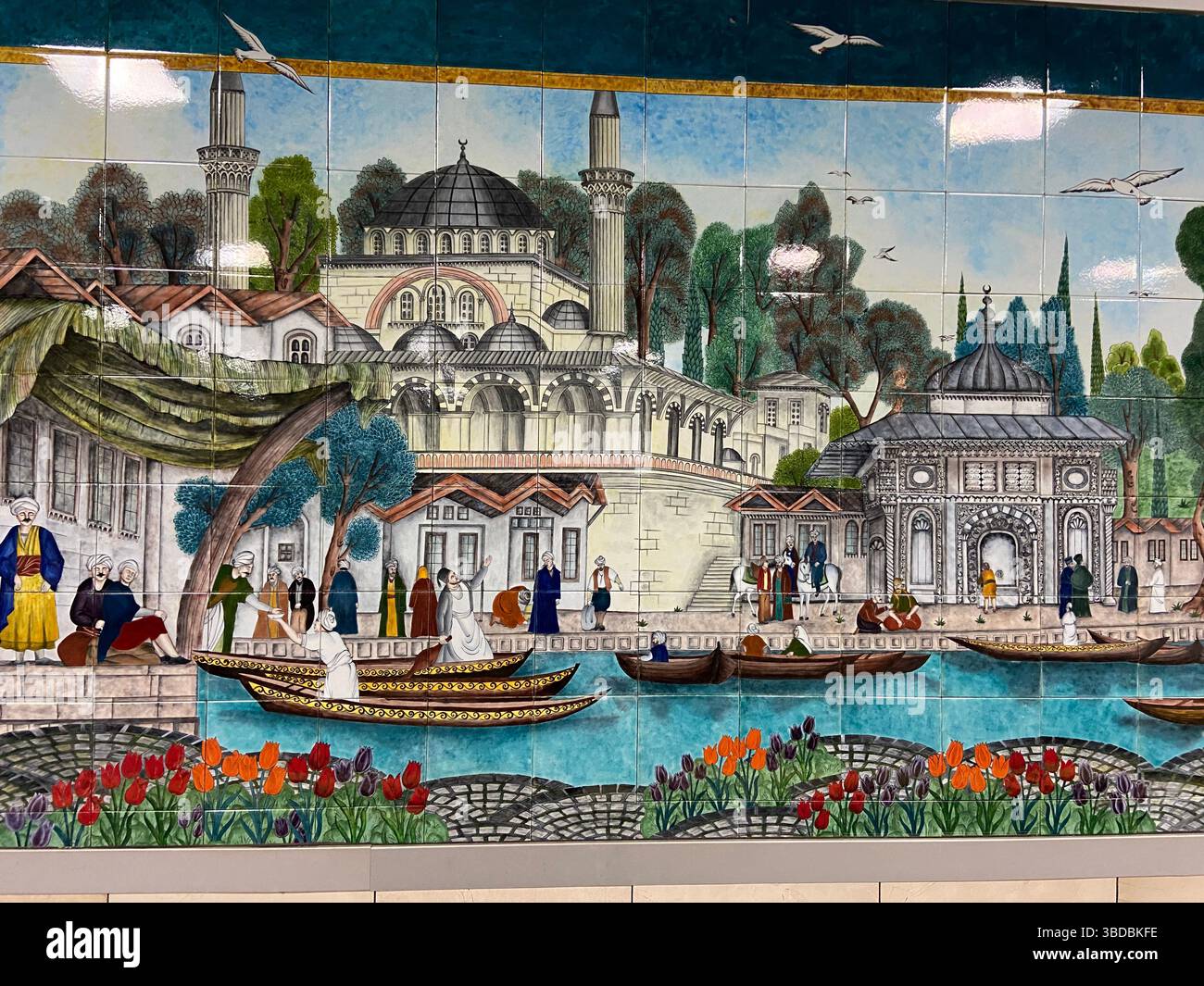 Une décoration murale colorée de style ottoman représentant une scène historique avec des gens, des bateaux et des éléments architecturaux à Istanbul. Banque D'Images