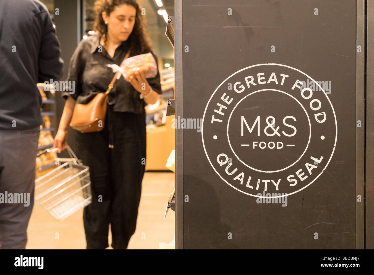 Shopper sélectionne des produits dans l'allée M&S portant la marque « The Great Food, Quality Seal » au supermarché Marks and Spencer Londres Angleterre, Royaume-Uni Banque D'Images