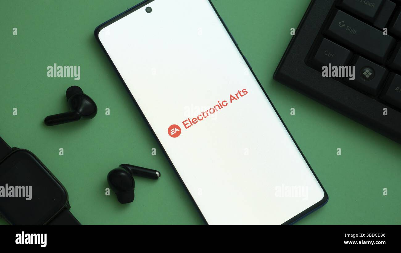 Smartphone affichant le logo Electronic Arts avec des accessoires technologiques sur vert Banque D'Images