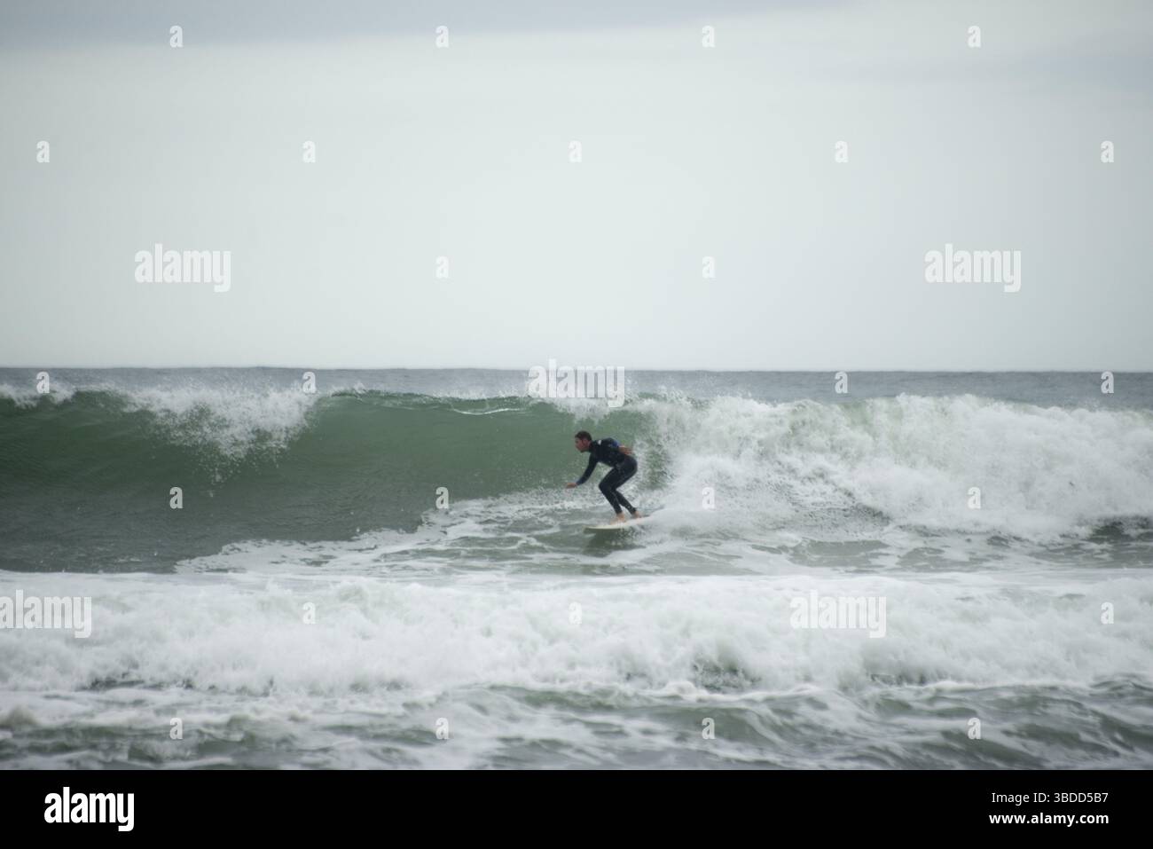 Un homme attrape une vague sur sa planche de surf dans une zone appelée Banque D'Images