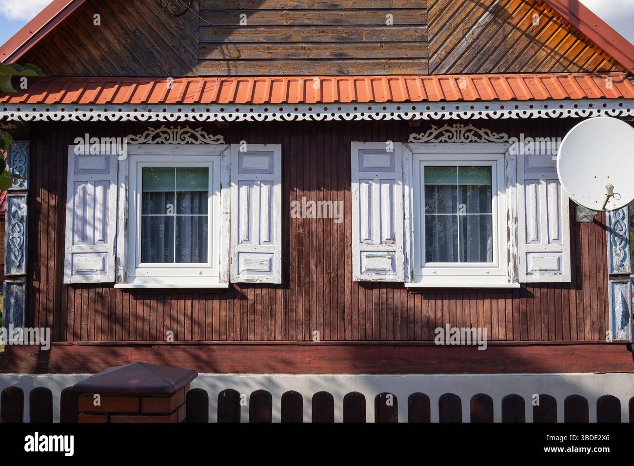 Une maison avec deux fenêtres et un toit rouge. La maison est ancienne et a une atmosphère rustique Banque D'Images