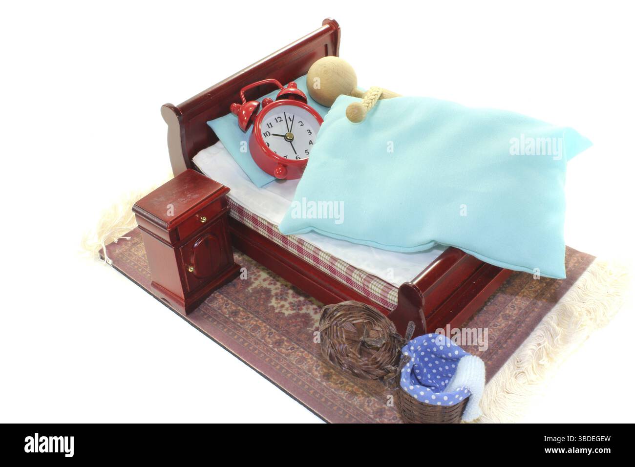 Dormir dans, une poupée en bois et réveil dans le lit avec armoire de chevet et linge de lit bleu Banque D'Images