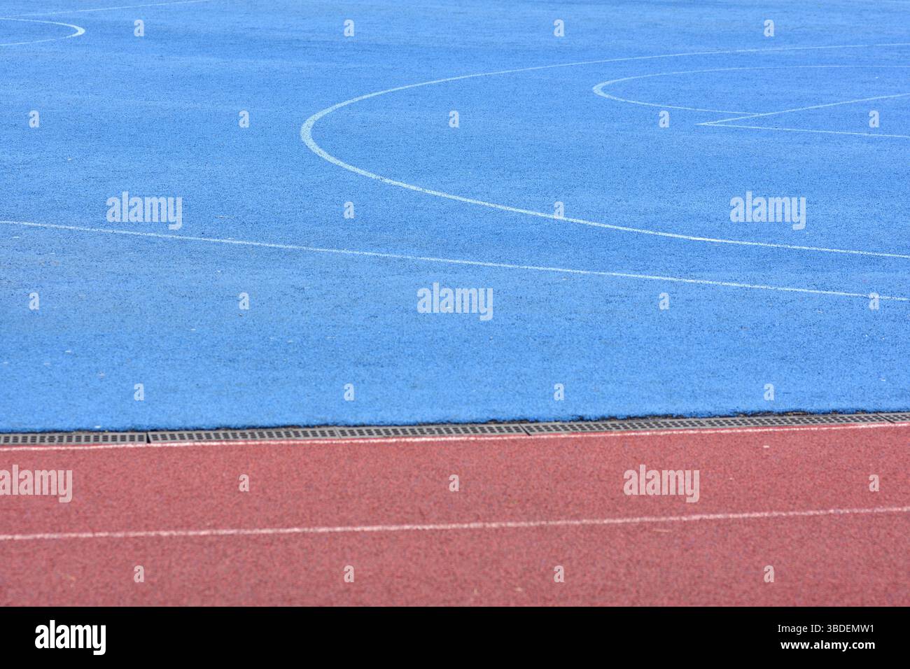 Piste de course rouge et terrain de sport bleu. Terrain de jeu de basket-ball vide avec piste de course de stade rouge dans le fond. Banque D'Images