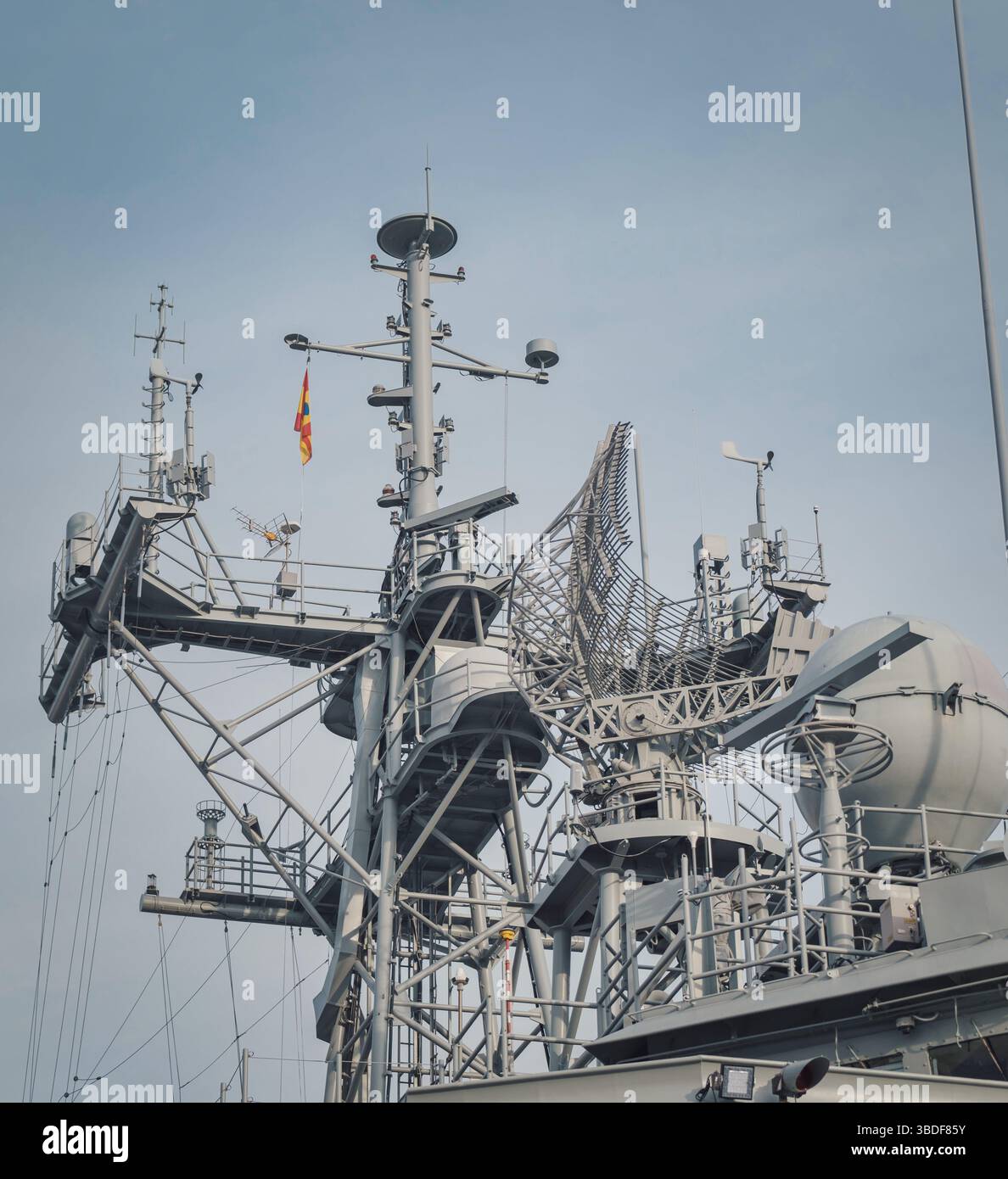 Vue rapprochée du mât d'un navire avec radar et équipement de communication perfectionné, y compris antennes et capteurs. Un drapeau signale la nationalité ou Banque D'Images