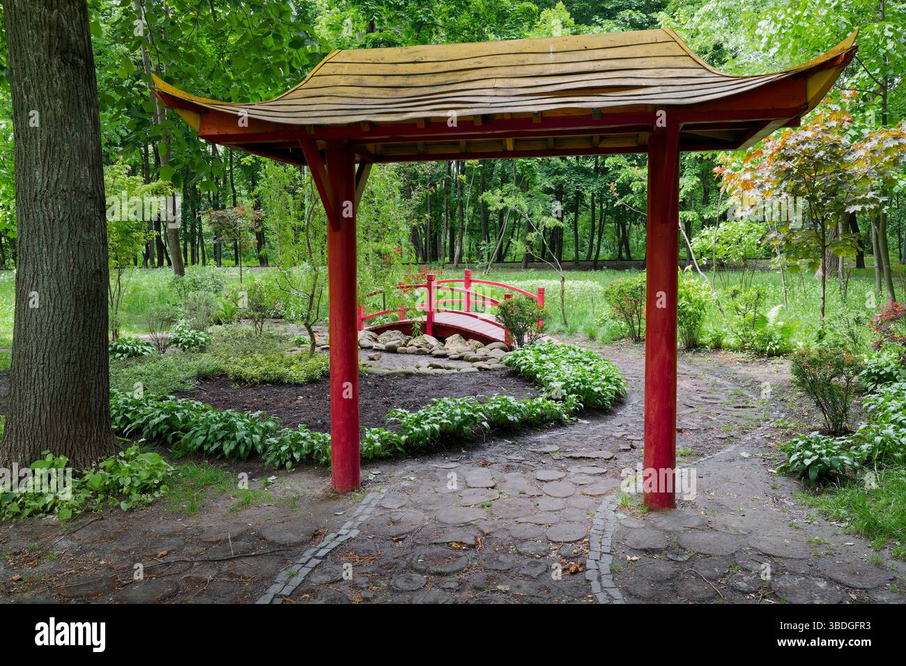 Un arc rouge dans le style oriental sur fond de verdure fraîche, installé dans un parc de Kiev Banque D'Images