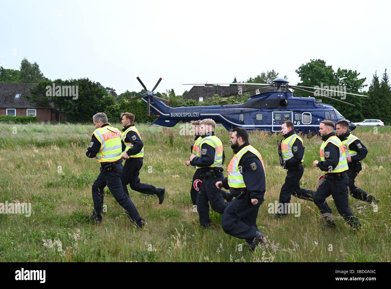 Nordhorn, Allemagne. 24 mai 2025. Les policiers fédéraux se rendent à pied à un poste de contrôle temporaire sur la route fédérale B213 après avoir été déposés par un hélicoptère de police (l). L'opération prioritaire a lieu dans le cadre du rétablissement temporaire des contrôles aux frontières intérieures le long de la frontière entre la basse-Saxe et les pays-Bas. Crédit : Lars Penning/dpa/Alamy Live News Banque D'Images