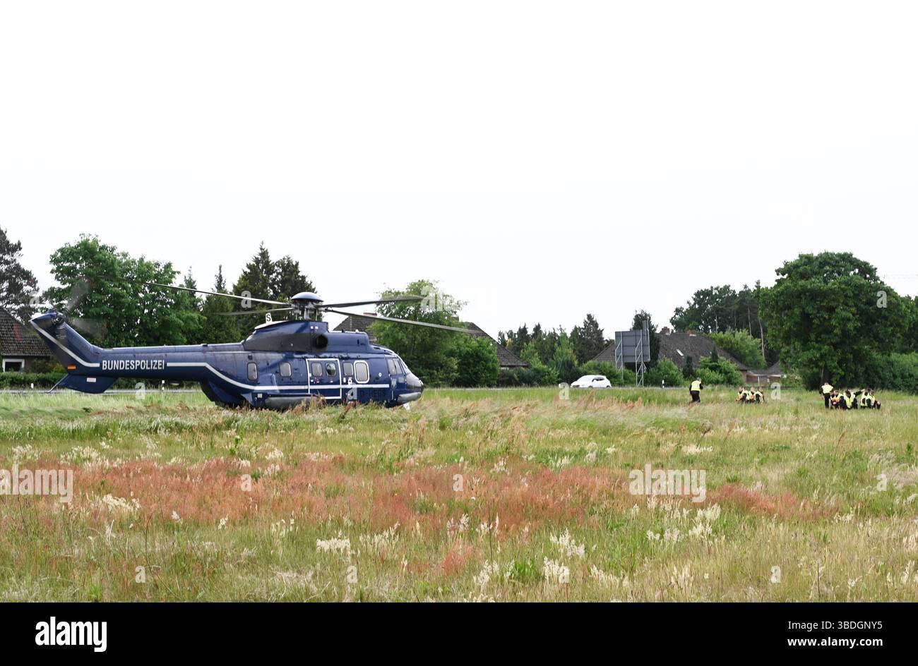 Nordhorn, Allemagne. 24 mai 2025. Les policiers fédéraux se rendent à pied à un poste de contrôle temporaire sur la route fédérale B213 après avoir été déposés par un hélicoptère de police (l). L'opération prioritaire a lieu dans le cadre du rétablissement temporaire des contrôles aux frontières intérieures le long de la frontière entre la basse-Saxe et les pays-Bas. Crédit : Lars Penning/dpa/Alamy Live News Banque D'Images