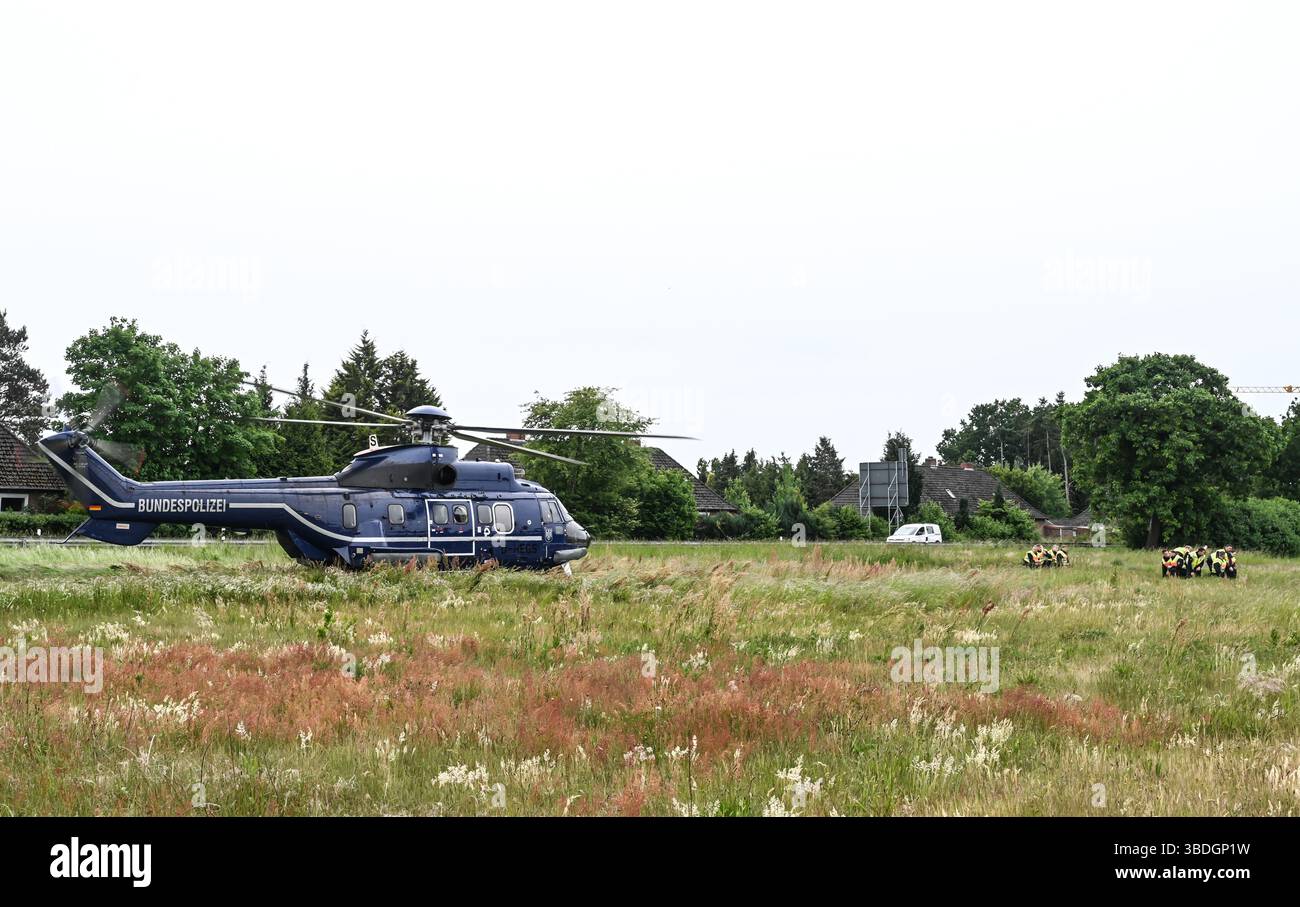 Nordhorn, Allemagne. 24 mai 2025. Les policiers fédéraux se rendent à pied à un poste de contrôle temporaire sur la route fédérale B213 après avoir été déposés par un hélicoptère de police (l). L'opération prioritaire a lieu dans le cadre du rétablissement temporaire des contrôles aux frontières intérieures le long de la frontière entre la basse-Saxe et les pays-Bas. Crédit : Lars Penning/dpa/Alamy Live News Banque D'Images