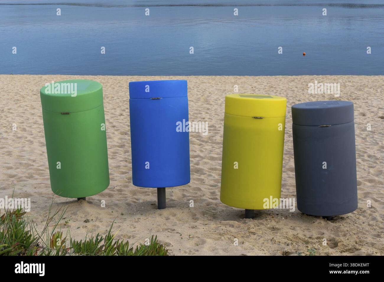 Quatre bacs de recyclage colorés sur une plage de sable Banque D'Images