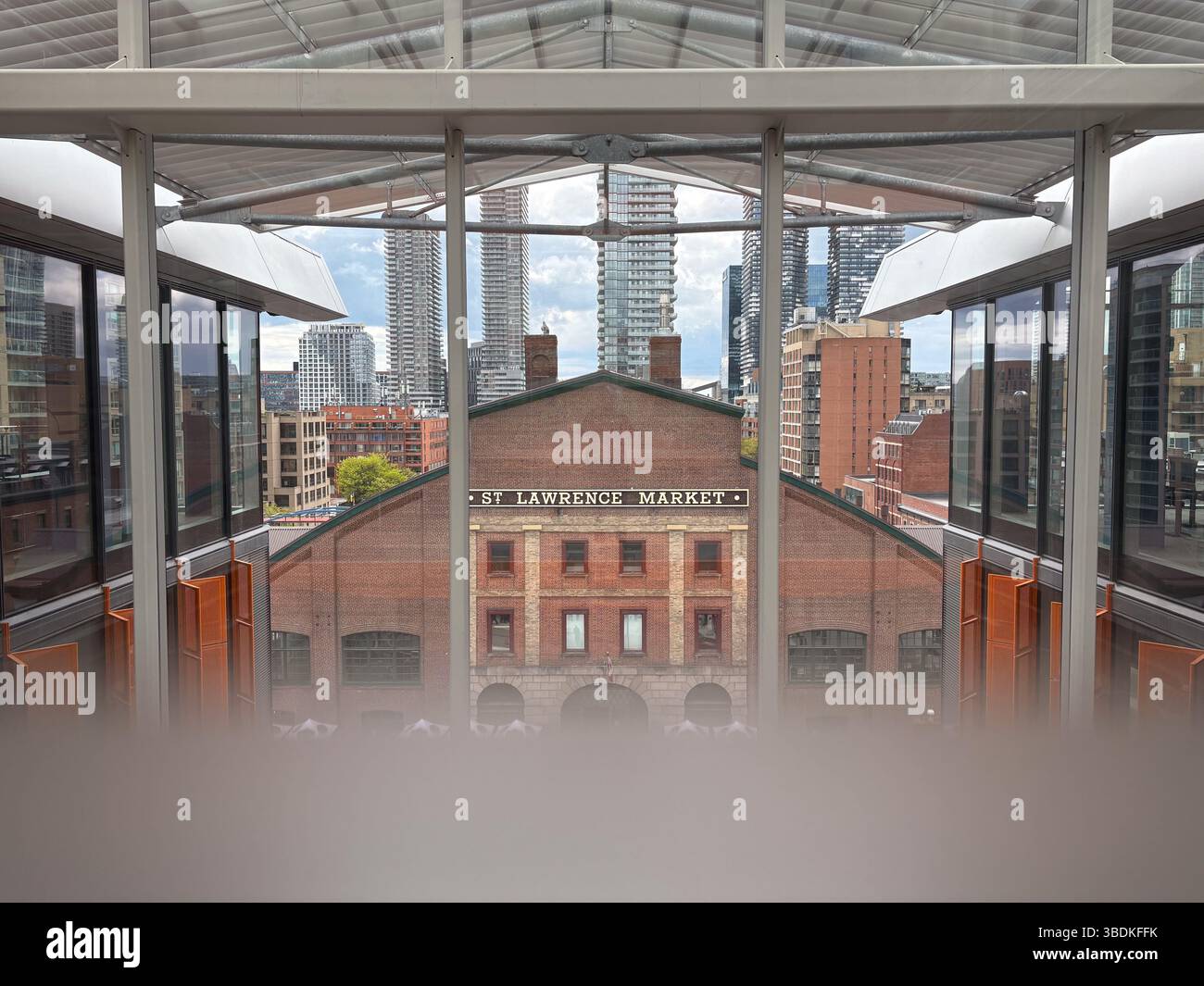 Lawrence Market, Toronto. Bâtiment historique du marché en briques rouges encadré par une architecture moderne avec la ligne d'horizon du centre-ville en arrière-plan. Banque D'Images