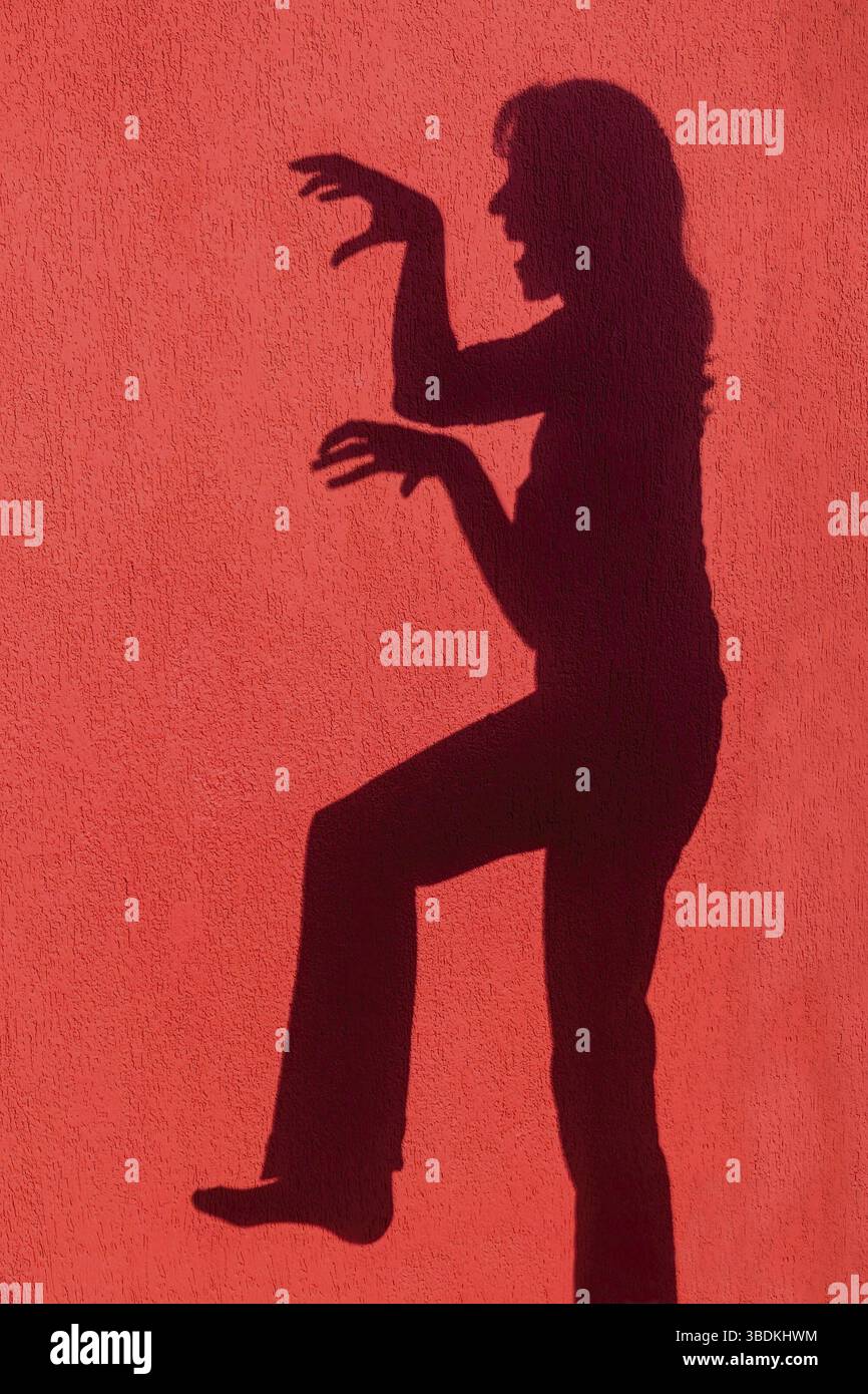 Ombre silhouette de femme en colère on red wall Banque D'Images
