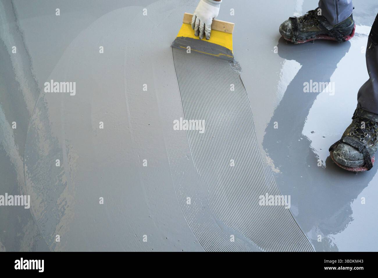 Un travailleur de la construction rénove balcon surface et s'étend de la colle et résine étanche avant de chipping et étanchéité Banque D'Images