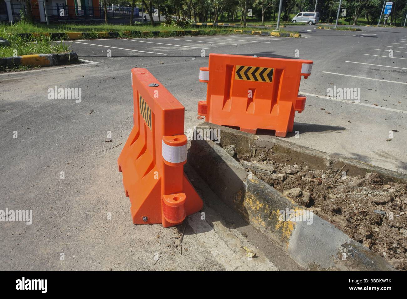 deux barrières routières oranges installées au milieu d’une route en réparation pendant la journée. Banque D'Images