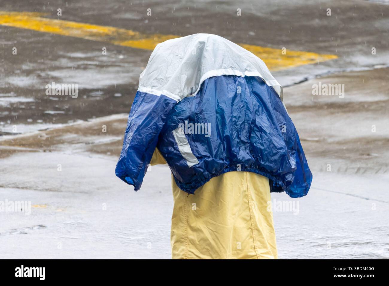 Personne protège sa tête avec une veste imperméable de la pluie dans une rue de ville Banque D'Images
