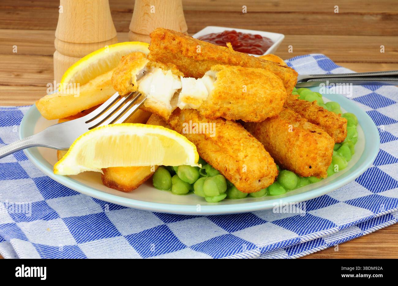 Les doigts de poisson et les chips couverts de pâte à frire sont repas avec des petits pois sur fond de bois Banque D'Images