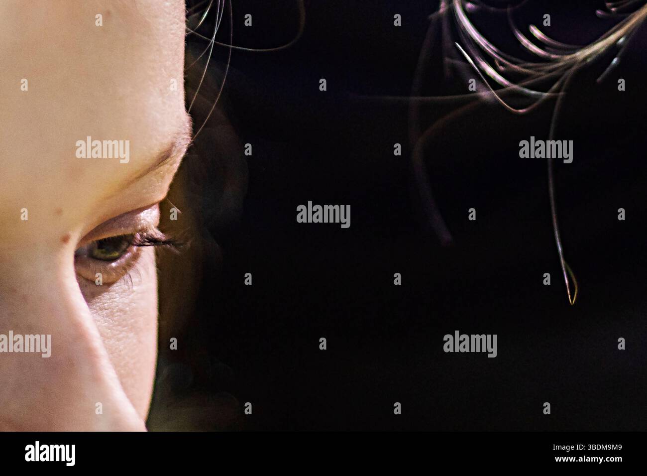 gros plan de l'œil d'une fille réfléchie sur un fond sombre illuminé par le soleil Banque D'Images
