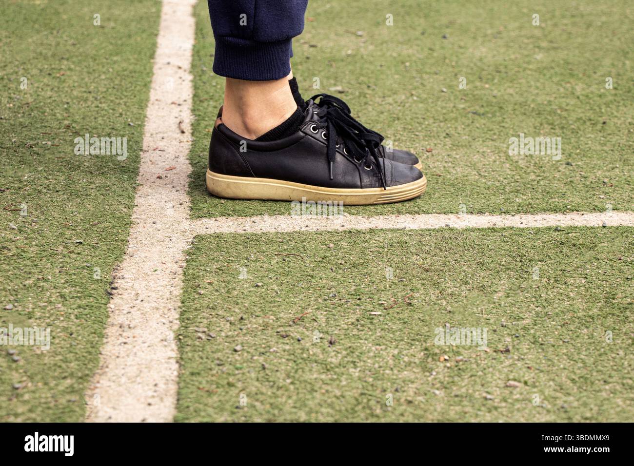 Jambes en baskets noires sur un terrain de football avec des marques, jouer au football Banque D'Images