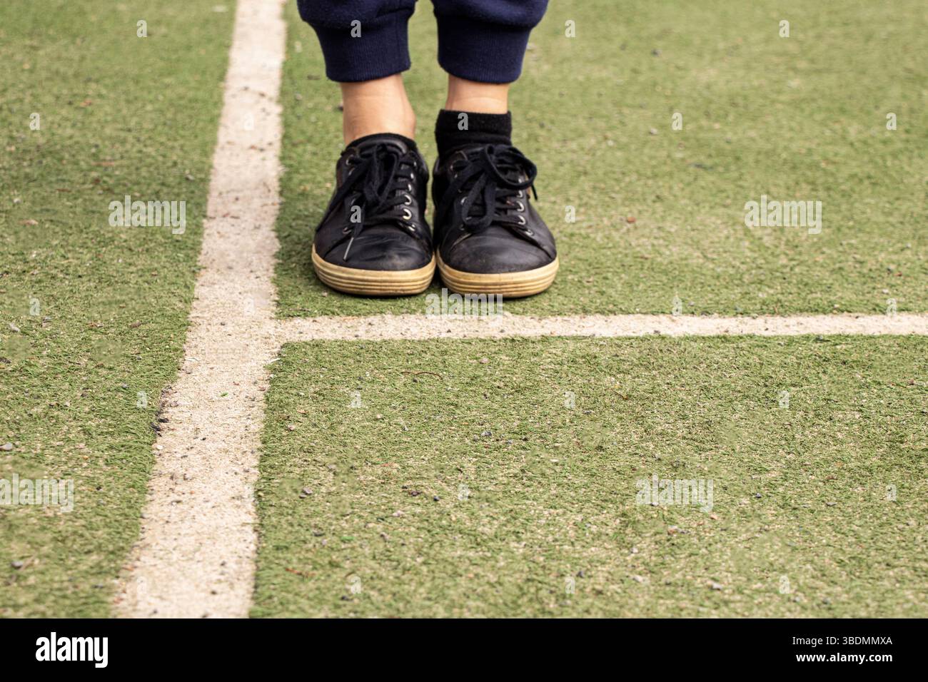 Jambes en baskets noires sur un terrain de football avec des marques, jouer au football Banque D'Images