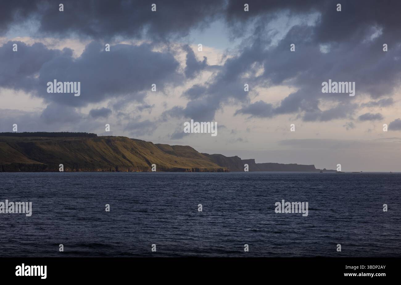 Lumière du soir sur les falaises escarpées le long de la côte de l'île de Skye, en Écosse, avec des nuages spectaculaires et un océan calme. Banque D'Images Lumière du soir sur les falaises escarpées le long de la côte de l'île de Skye, en Écosse, avec des nuages spectaculaires et un océan calme. Banque D'Images
