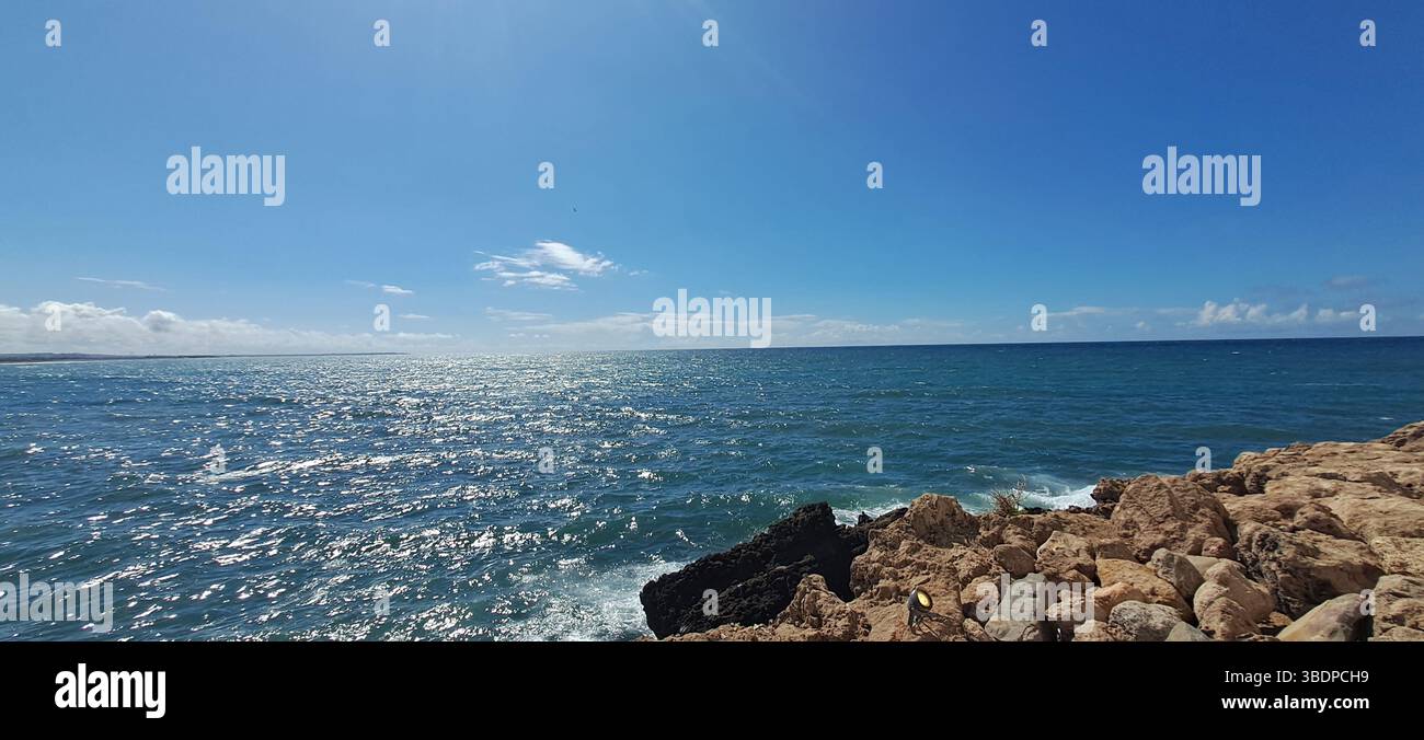 La lumière du soleil scintille sur l'océan sous un ciel bleu clair Banque D'Images
