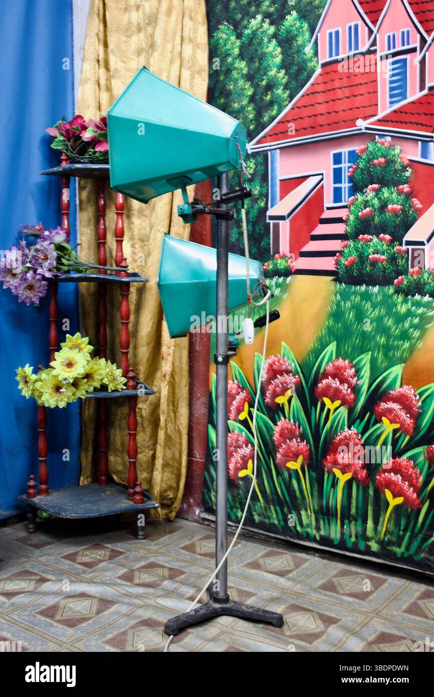 Un studio de portrait rétro à Gazipur, au Bangladesh, avec des décors peints vibrants et des lumières de scène simulant une scène de maison et de jardin. Banque D'Images
