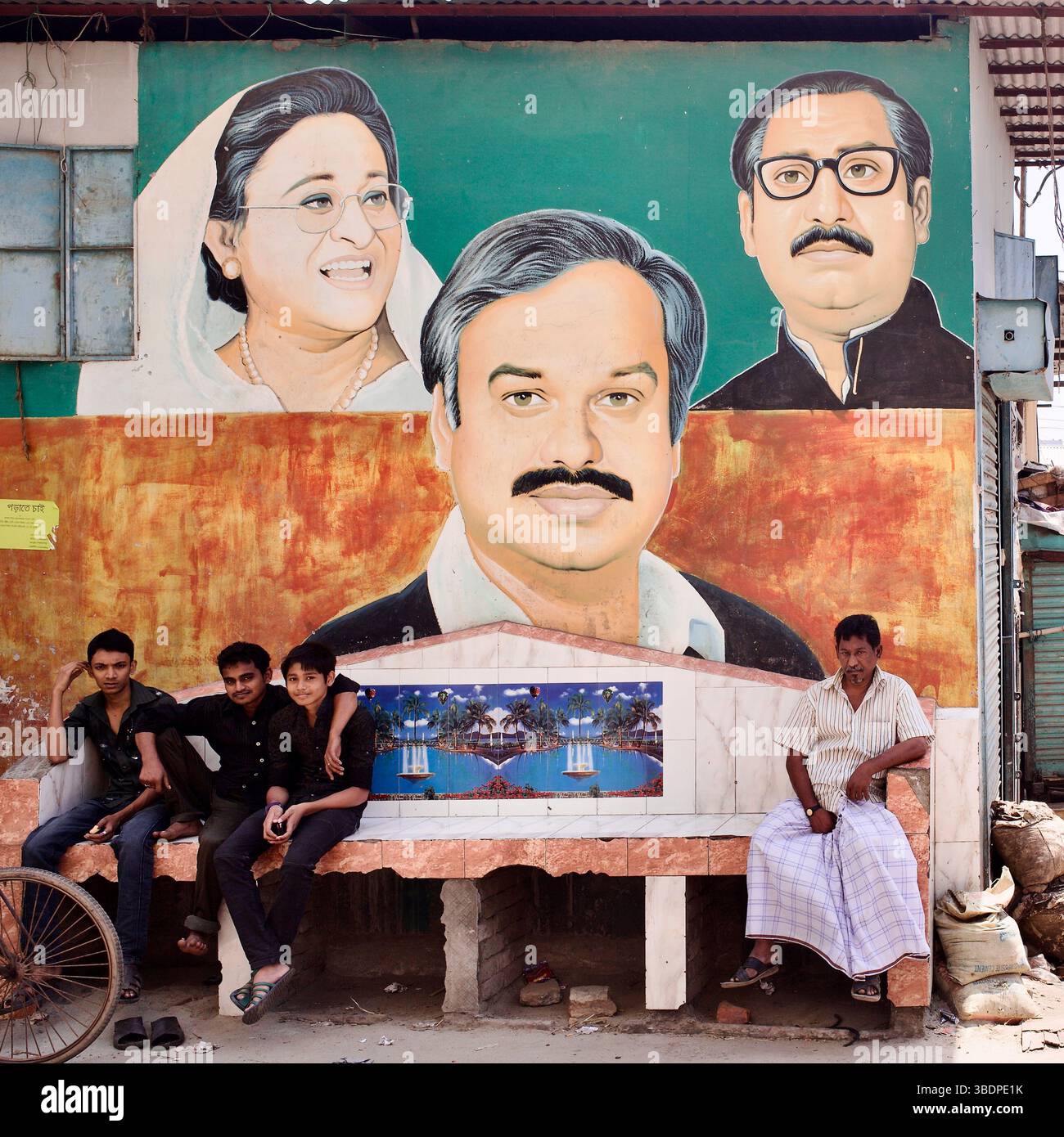 Murale de rue à Cox’s Bazar, au Bangladesh, avec Sheikh Hasina, Sheikh Mujibur Rahman et une figure locale de la Ligue Awami à côté d’un banc en bord de route. Banque D'Images