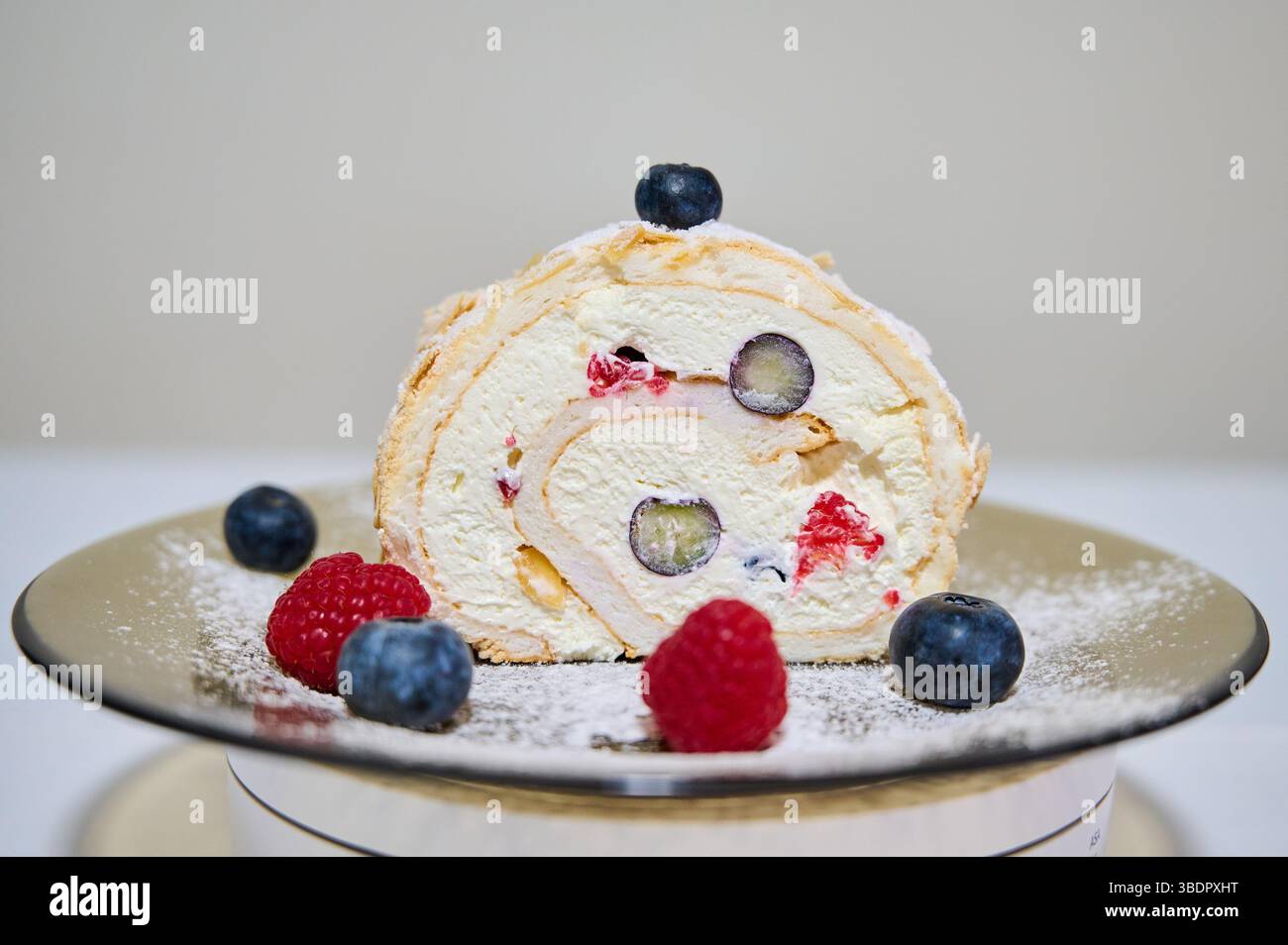 Rouler le gâteau avec la crème, la framboise et les myrtilles Banque D'Images