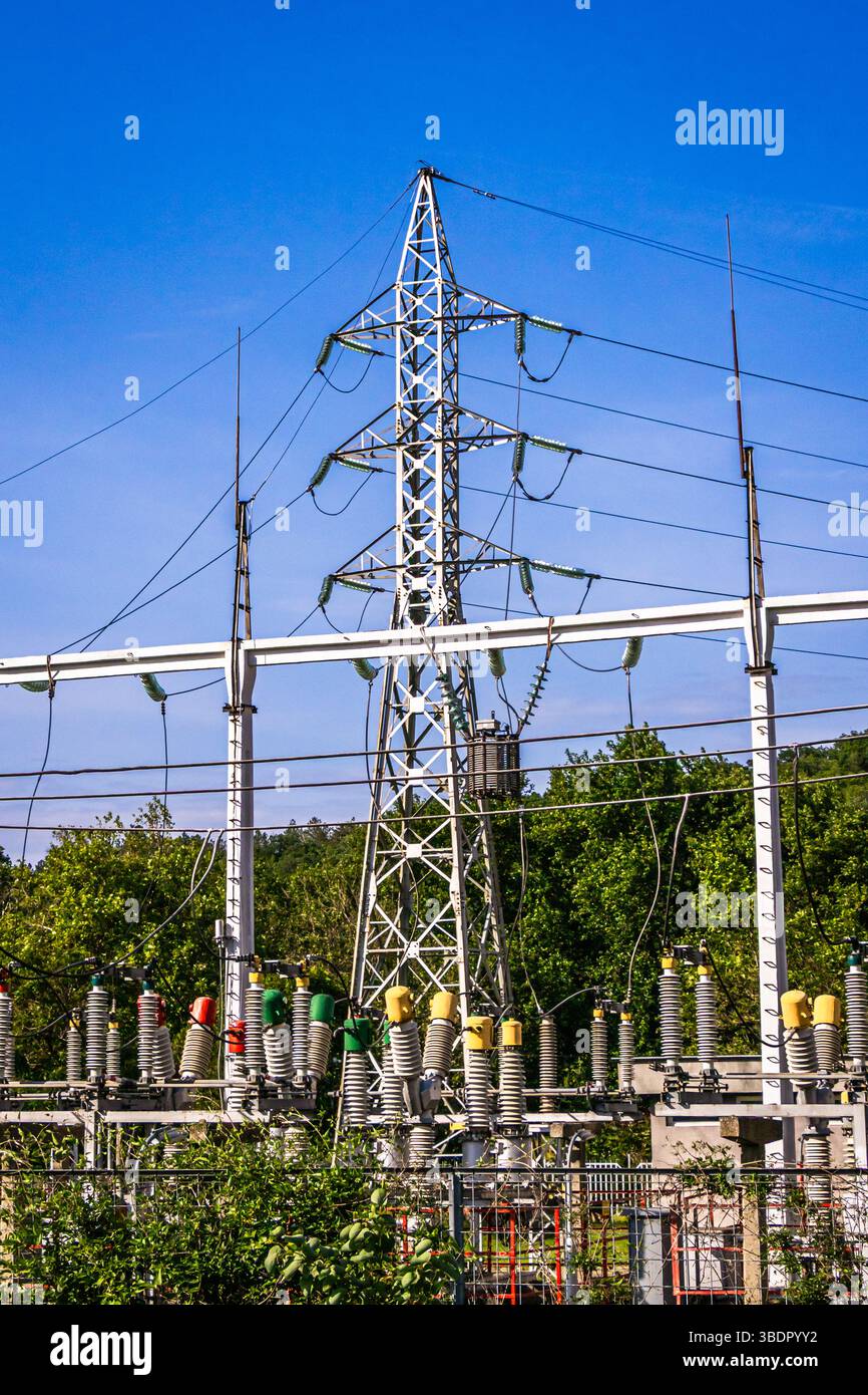 Une grande tour de transmission d'énergie électrique se dresse bien en évidence contre un ciel bleu vif, entourée d'une sous-station bien entretenue avec de nombreuses insula Banque D'Images