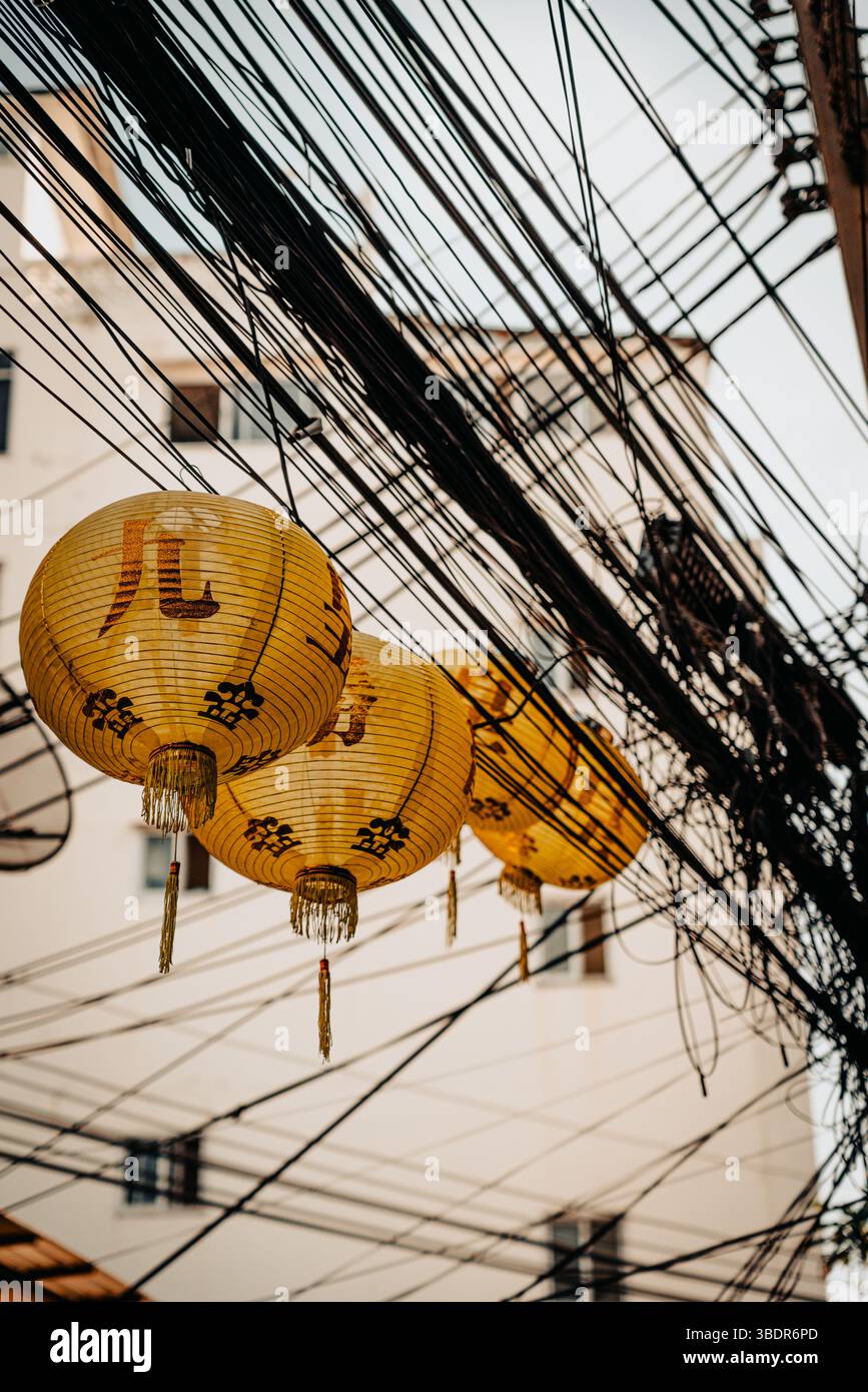 Scène thaïlandaise urbaine avec des lanternes Khom Pha accrochées aux lignes électriques, mettant en valeur la culture thaïlandaise traditionnelle Banque D'Images