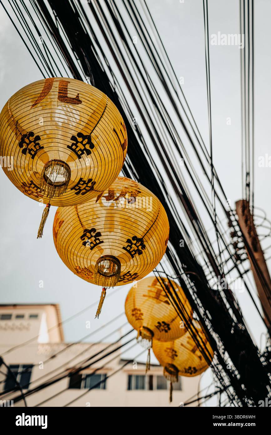 Scène thaïlandaise urbaine avec des lanternes Khom Pha accrochées aux lignes électriques, mettant en valeur la culture thaïlandaise traditionnelle Banque D'Images
