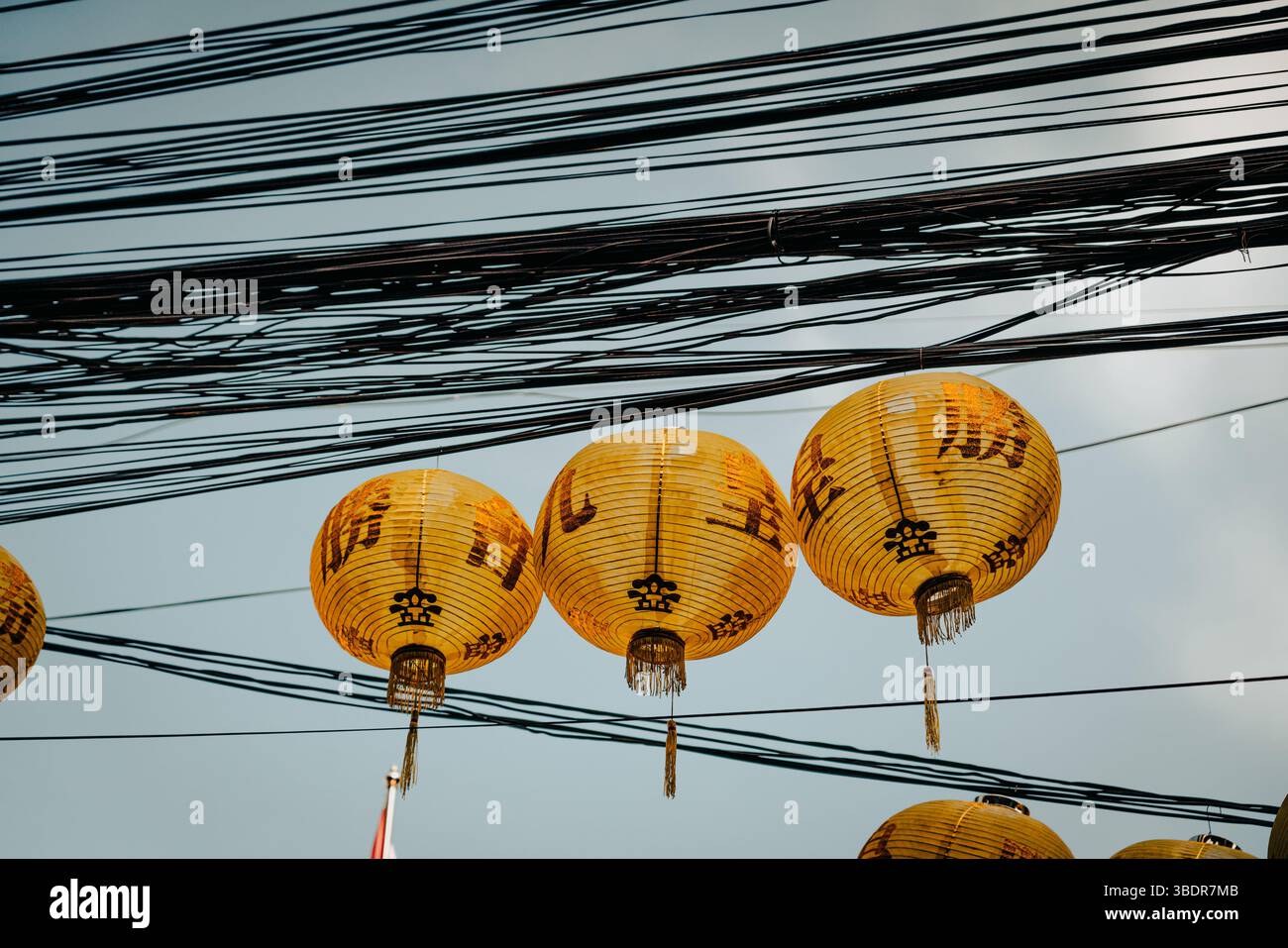 Scène thaïlandaise urbaine avec des lanternes Khom Pha suspendues à des lignes électriques, capturant l'essence de la culture thaïlandaise traditionnelle et l'atmosphère de rue Banque D'Images
