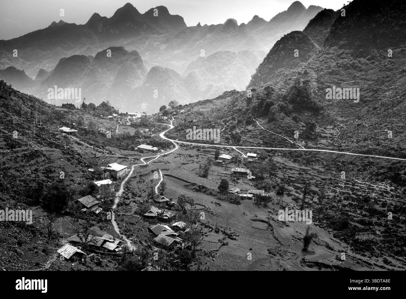 Au milieu des majestueuses montagnes de Hà Giang, un village paisible émerge avec des maisons simples et des chemins sinueux qui s'étendent à flanc de colline. Le souffle Banque D'Images