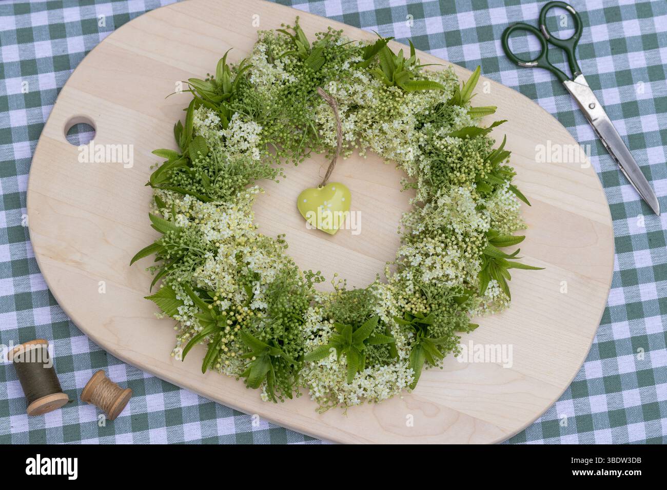 couronne florale avec fleurs de sureau et fruits de cornbeam sur une planche de bois Banque D'Images