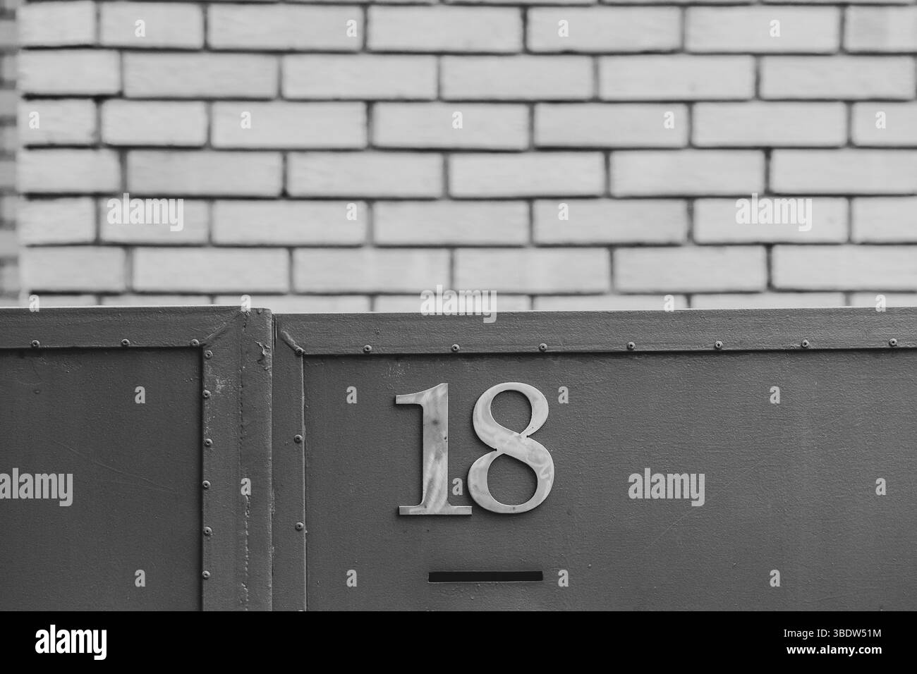 Numéro 18 – marque d'entrée sur fond de métal et de brique. Teintes monochromes. Banque D'Images