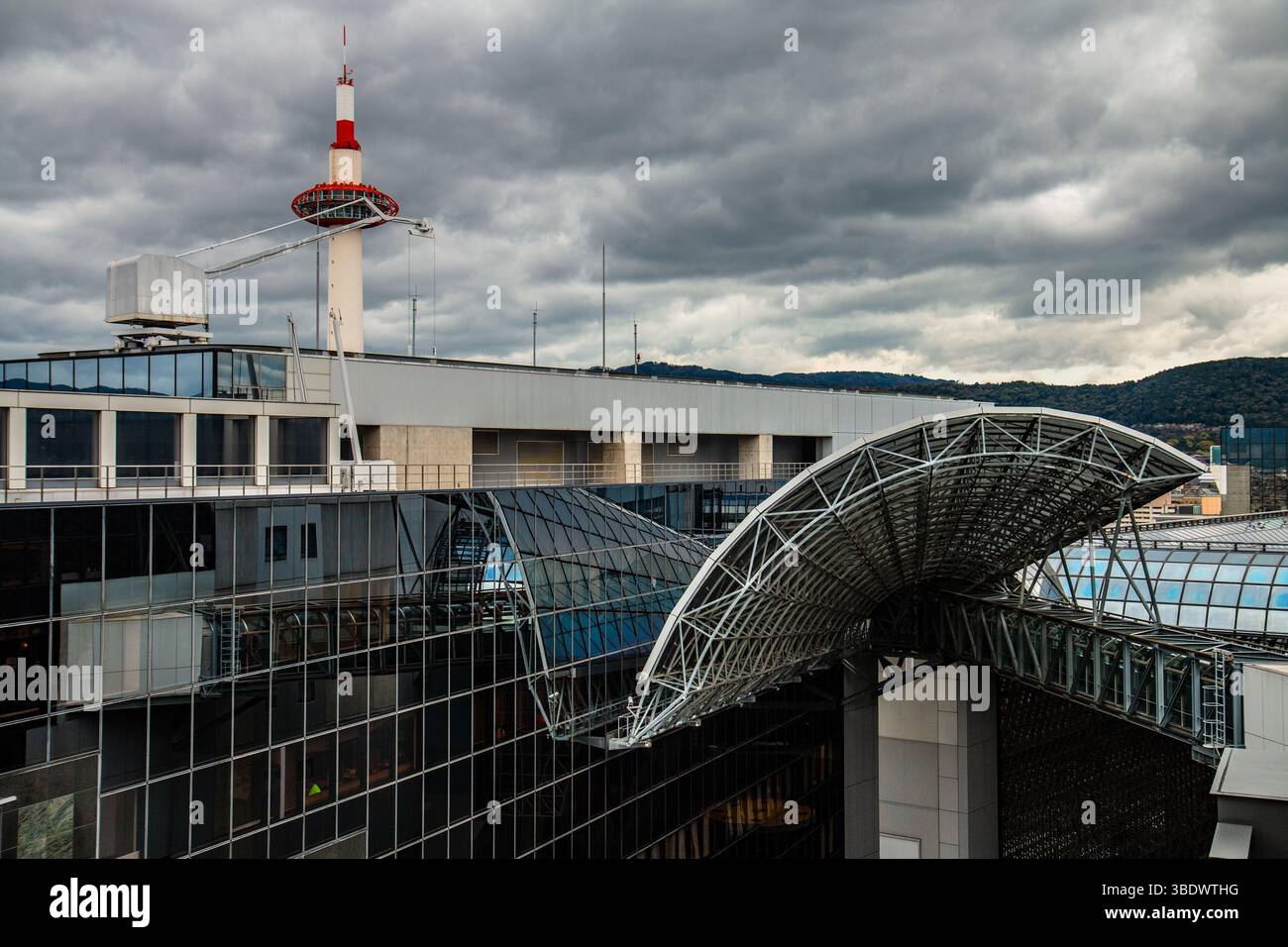 Le toit emblématique de la canopée de la gare de Kyoto et la tour adjacente se dressent contre un ciel nuageux spectaculaire, illustrant l'échelle urbaine et le design Banque D'Images