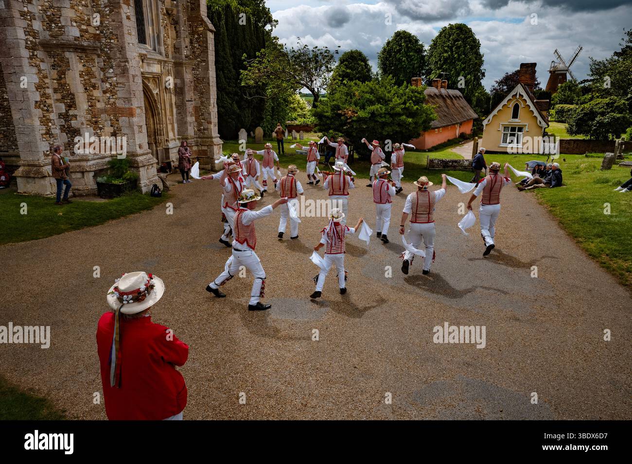 Thaxted, Royaume-Uni. 26 mai 2025. Thaxted May Bank Holiday Morris Dancing-26 mai 2025  les danseurs de Thaxted Morris se produisent dans la cour de l'église sous un ciel de plomb avec les Alms Houses et Thaxted Windmill comme toile de fond lors d'un lundi de vacances froid et humide. Crédit photographique : BRIAN HARRIS/Alamy Live News Banque D'Images