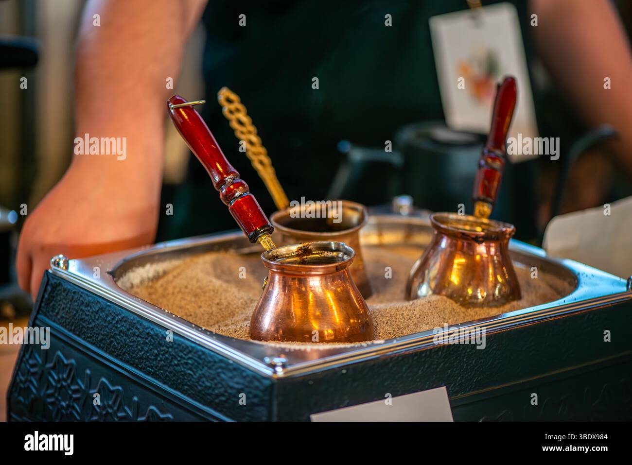 Une cafetière turque traditionnelle, connue sous le nom de « cezve », est vue bouillante dans le sable chaud. Cette méthode de brassage authentique met en valeur le patrimoine culturel et le Banque D'Images