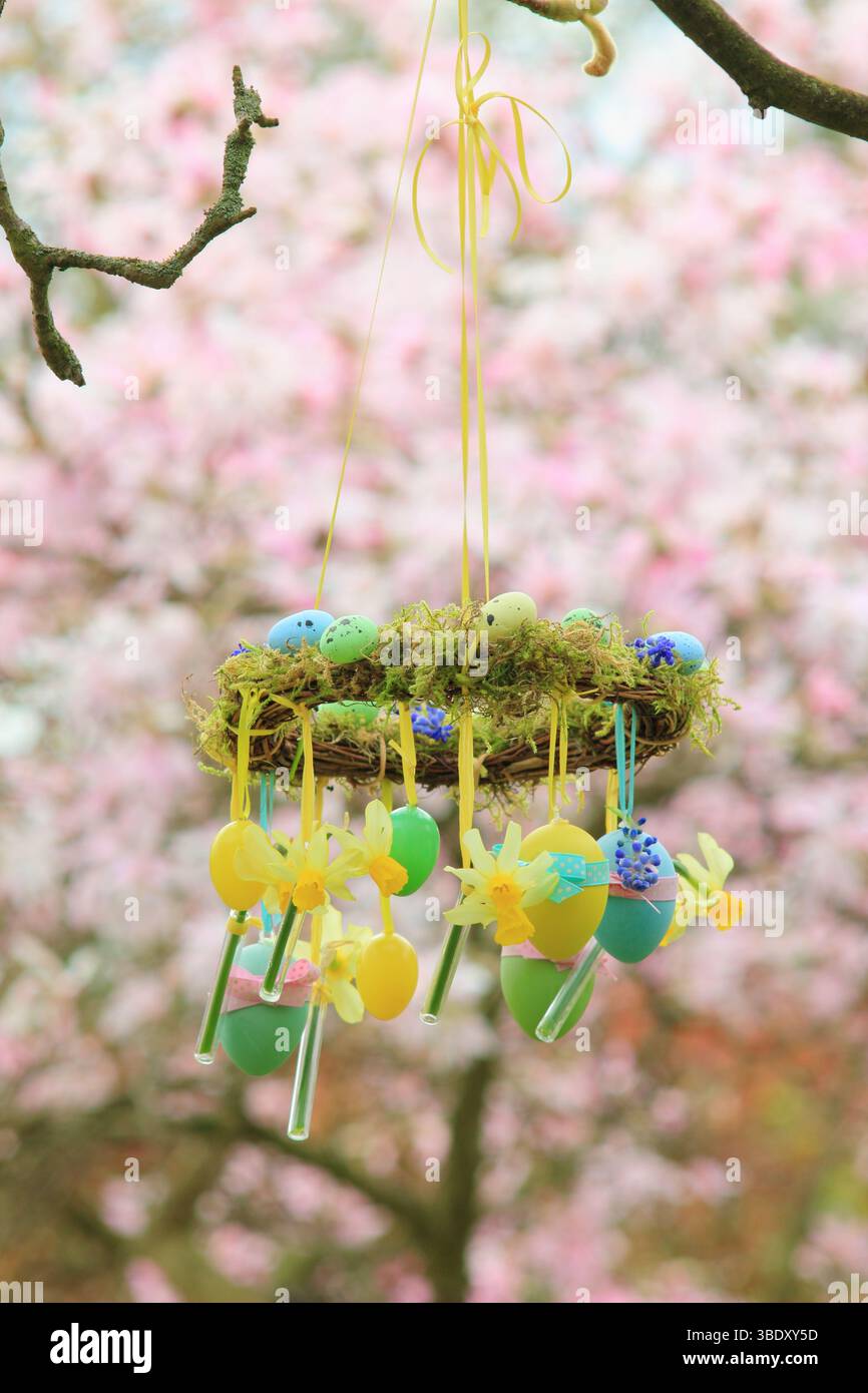 Couronne de Pâques. Projet de couronne facile à faire avec de la mousse, des jonquilles miniatures et un œuf de Pâques suspendu sur la branche de jardin avec un ruban jaune. ROYAUME-UNI Banque D'Images