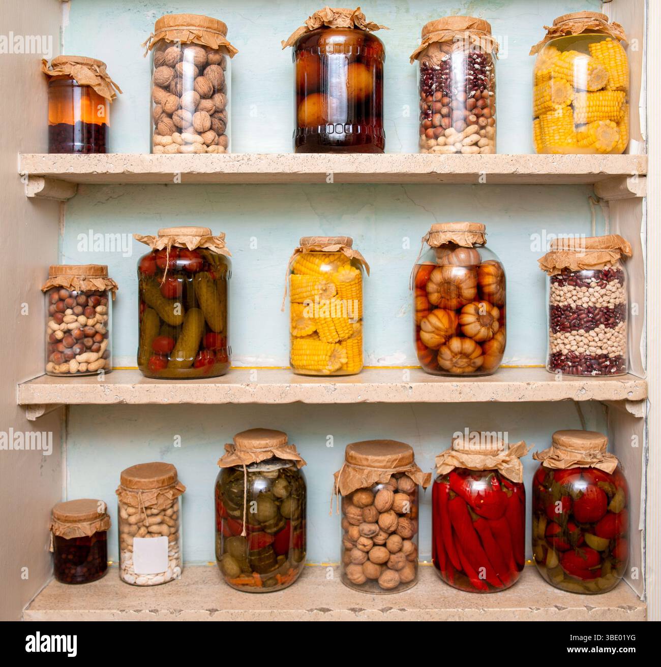 Une étagère de garde-manger de style vintage remplie de bocaux en verre de légumes conservés, de noix, de haricots et de maïs, évoquant la tradition maison et la durabilité. Banque D'Images