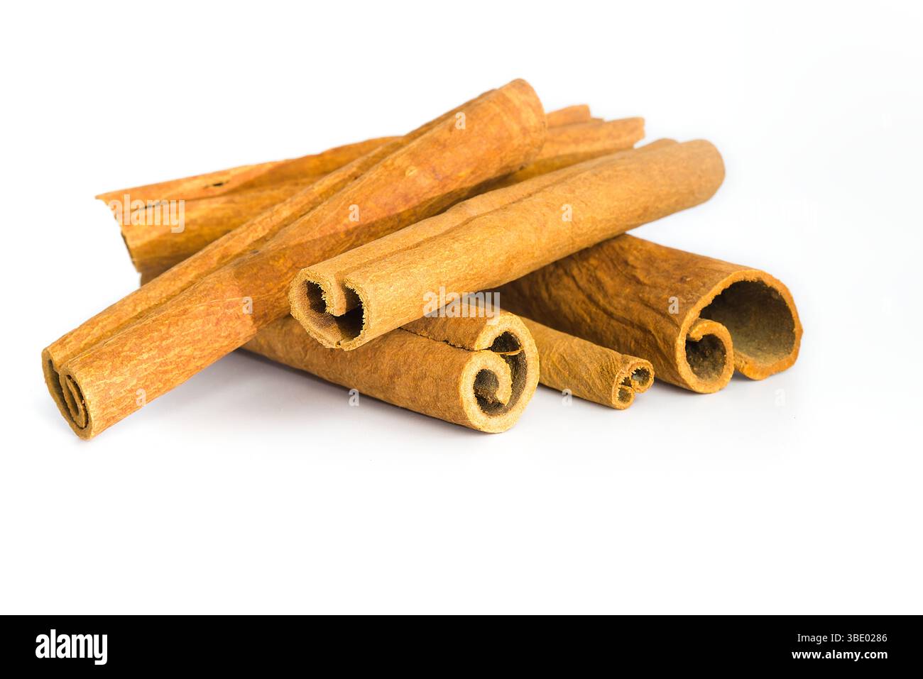 Morceaux d'écorce de cannelle répartis sur une surface blanche, soulignant leur texture fibreuse, leurs teintes terreuses et leurs courbes naturelles, parfaits pour le visu sur le thème des épices Banque D'Images