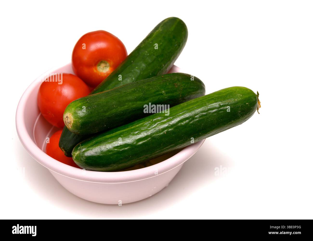 Tomates rouges vives et concombres croquants dans un bol en céramique sur une table, préparés pour une salade fraîche saine. Banque D'Images