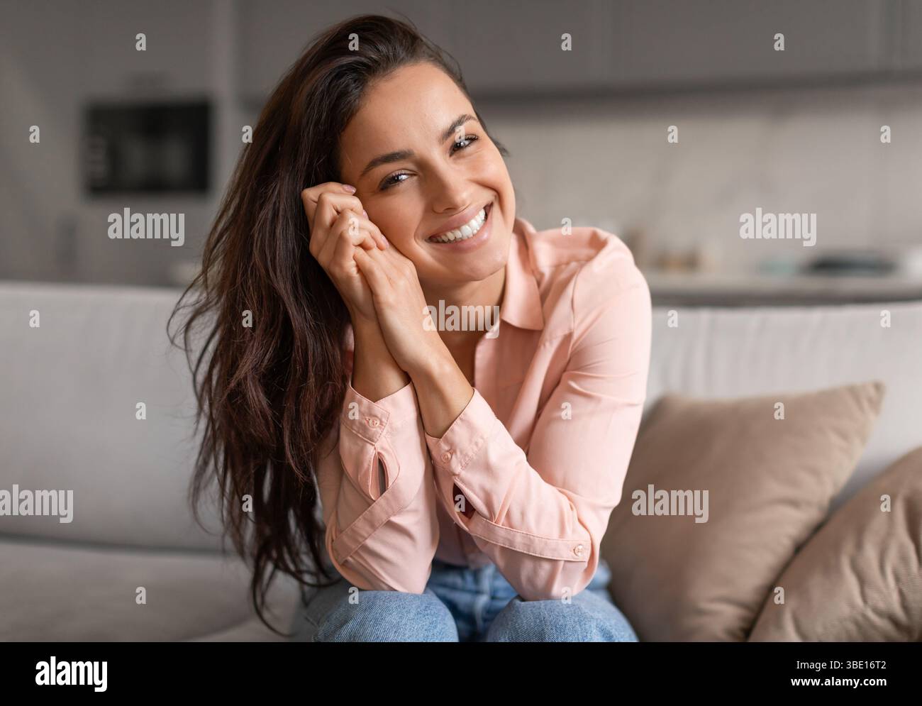 Jeune femme souriante posant avec désinvolture les mains sur le visage Banque D'Images