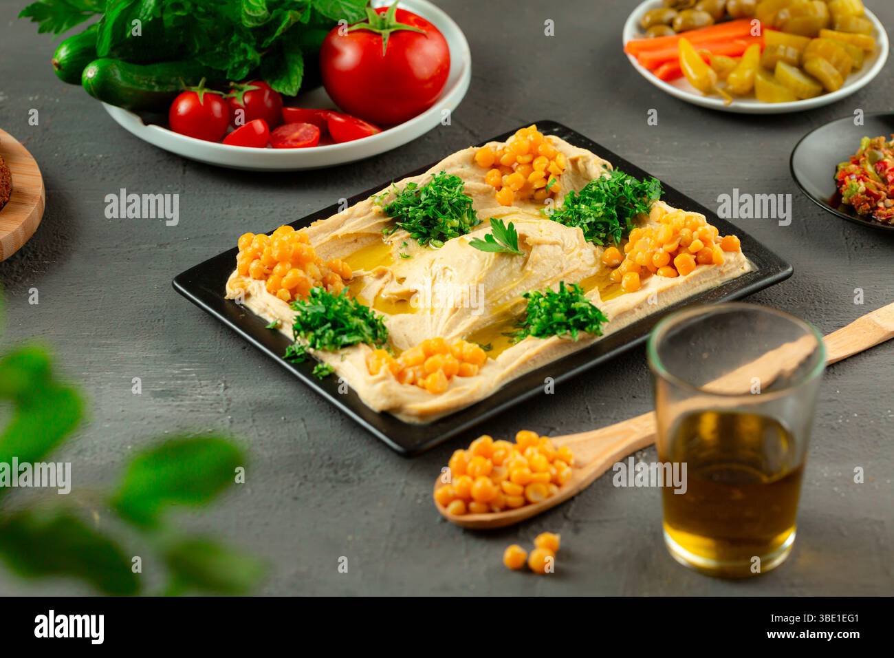 Bol de houmous servi avec de l’huile d’olive, des pois chiches et des garnitures traditionnelles – mezzé arabe Banque D'Images